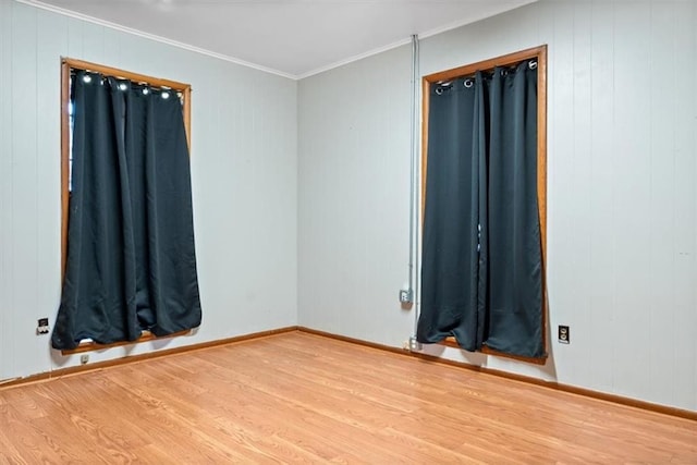 spare room with wooden walls, baseboards, ornamental molding, and wood finished floors