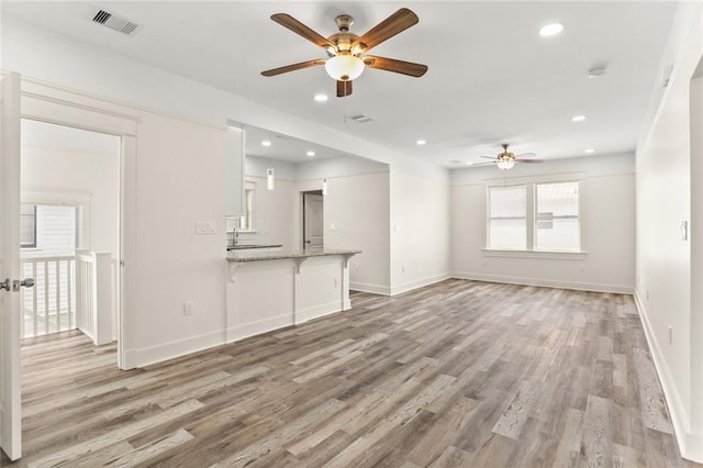 unfurnished living room featuring baseboards, ceiling fan, light wood-type flooring, and visible vents