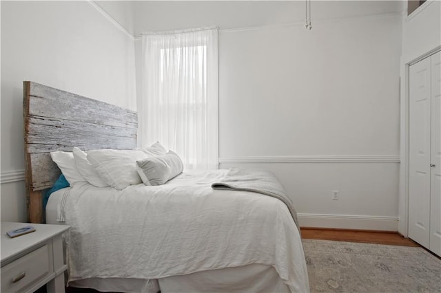 bedroom featuring baseboards, wood finished floors, and a closet