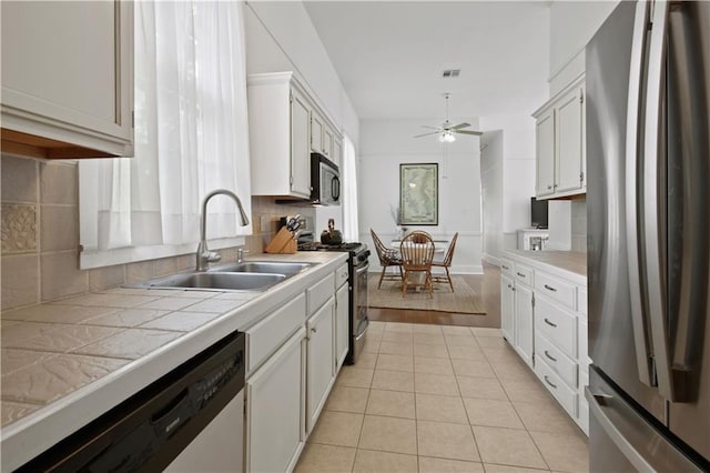kitchen featuring decorative backsplash, ceiling fan, tile countertops, a sink, and stainless steel appliances
