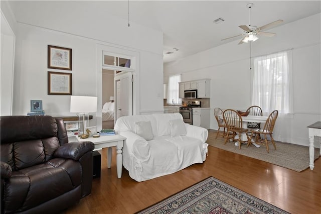 living area featuring a ceiling fan, wood finished floors, and visible vents