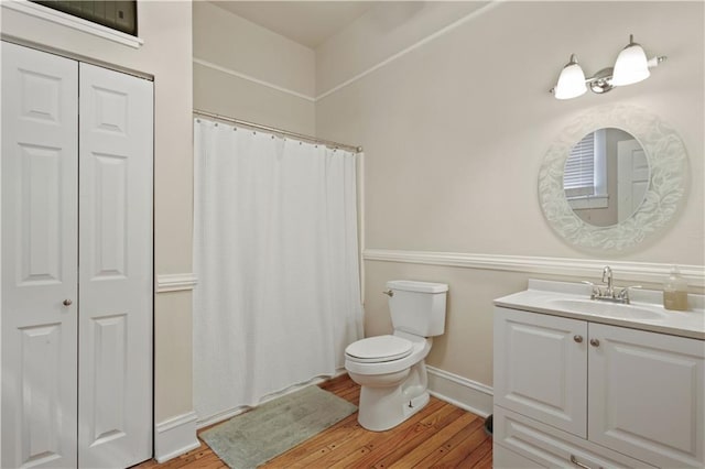 bathroom with vanity, wood finished floors, toilet, baseboards, and a shower with curtain