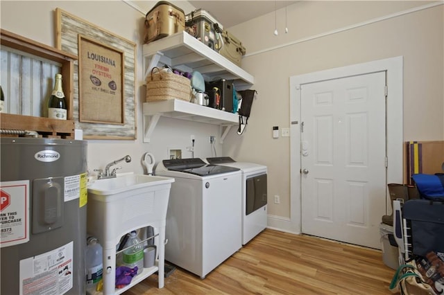 laundry area with laundry area, separate washer and dryer, a sink, light wood-style flooring, and water heater