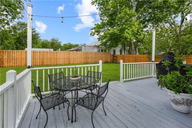 deck featuring a fenced backyard, outdoor dining area, and a lawn