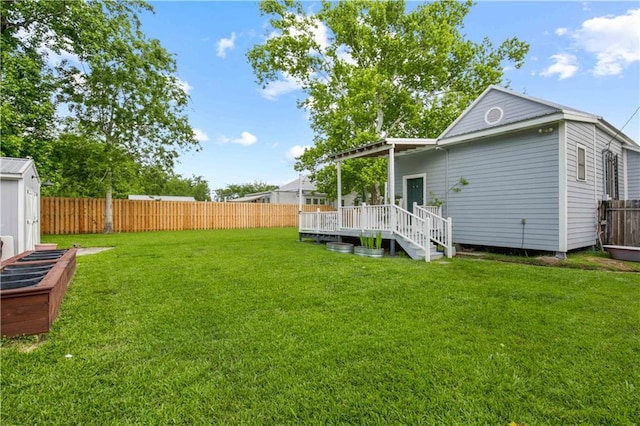 view of yard featuring a fenced backyard, a wooden deck, and an outbuilding