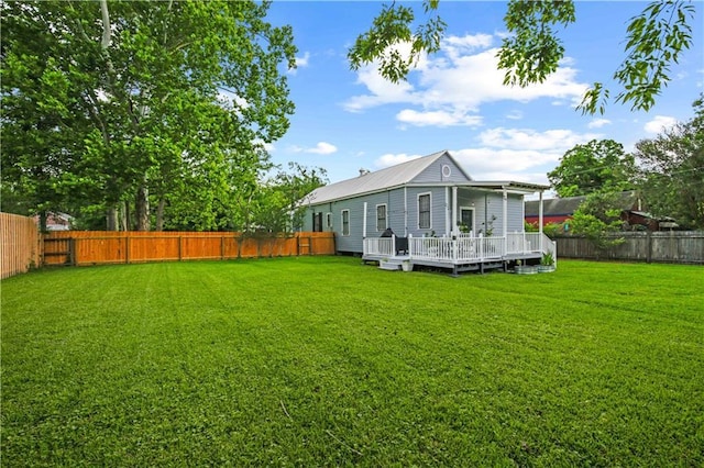 rear view of property featuring a lawn, a fenced backyard, and a deck