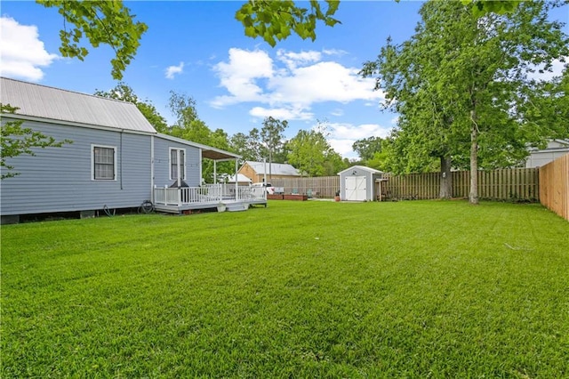 view of yard featuring a fenced backyard, a storage unit, a wooden deck, and an outdoor structure