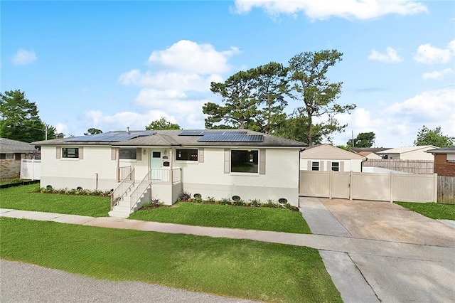 ranch-style house with roof mounted solar panels, a gate, concrete driveway, and a front yard