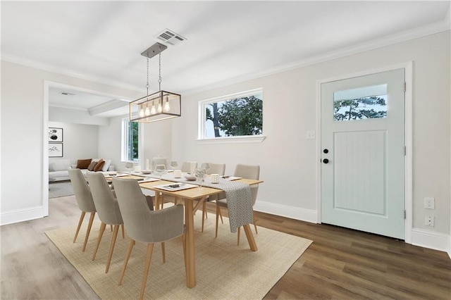 dining space with crown molding, baseboards, wood finished floors, and visible vents