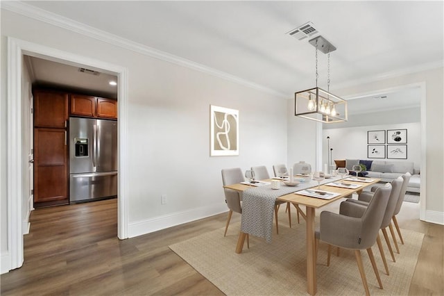 dining space with crown molding, baseboards, visible vents, and wood finished floors