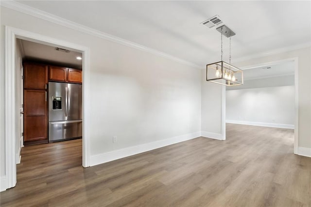 unfurnished dining area featuring crown molding, baseboards, wood finished floors, and visible vents