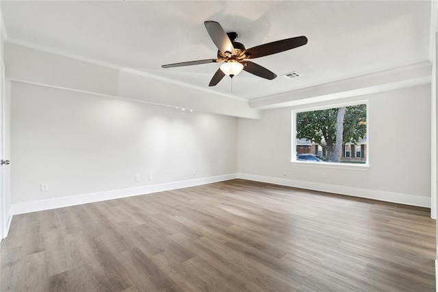 empty room featuring visible vents, a ceiling fan, baseboards, and wood finished floors
