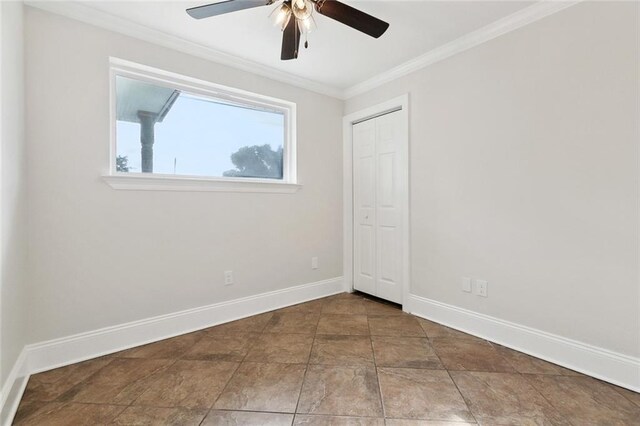 empty room with crown molding, baseboards, a ceiling fan, and stone finish flooring
