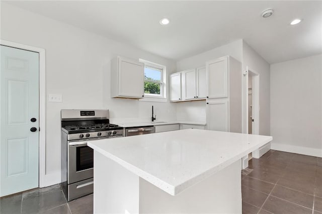 kitchen with a sink, white cabinets, stainless steel appliances, and dark tile patterned flooring