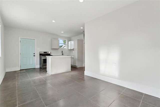 unfurnished living room with dark tile patterned flooring, recessed lighting, baseboards, and a sink