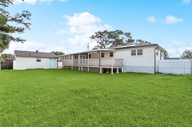 rear view of property with a lawn, a deck, and fence