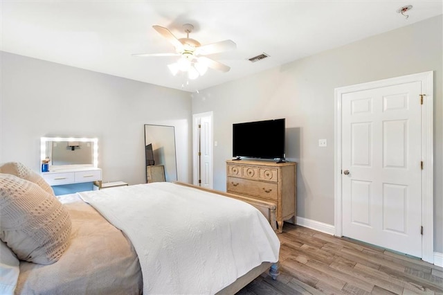 bedroom with visible vents, a ceiling fan, light wood-style floors, and baseboards