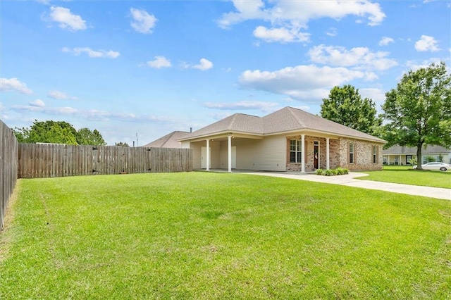back of property with brick siding, a fenced backyard, a yard, and driveway