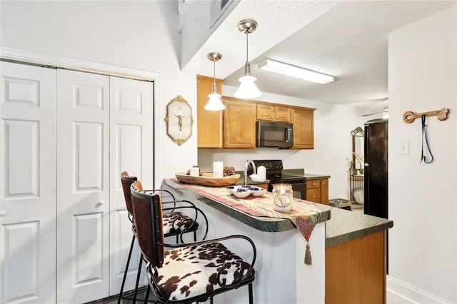 kitchen featuring dark countertops, black electric range, a peninsula, decorative light fixtures, and a kitchen bar