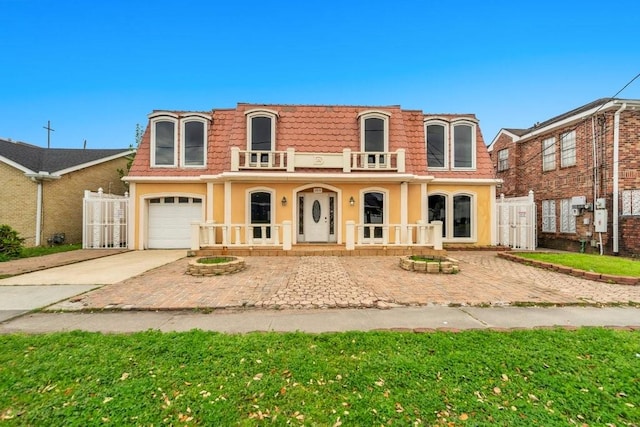view of front of property featuring covered porch, mansard roof, driveway, and a balcony