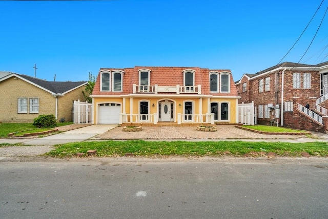 view of front of home featuring a porch, mansard roof, fence, concrete driveway, and stucco siding