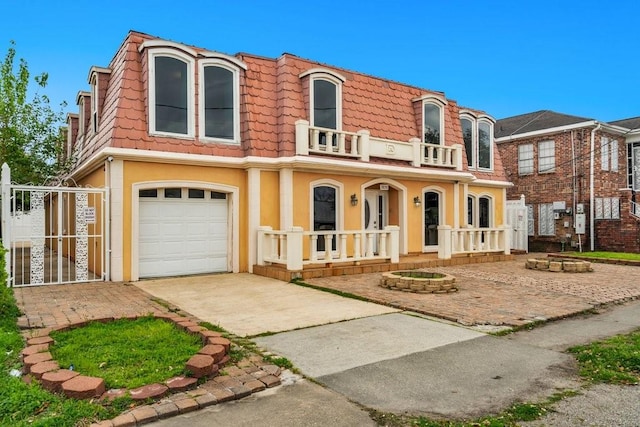view of front facade with a garage, a balcony, covered porch, concrete driveway, and a tile roof