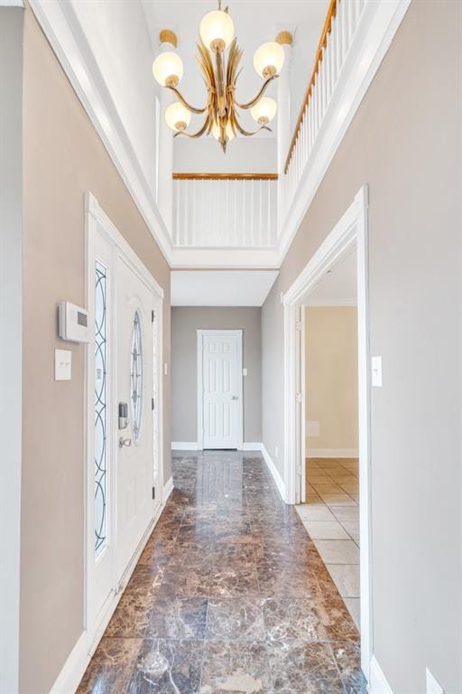 entrance foyer with baseboards, a notable chandelier, and a towering ceiling