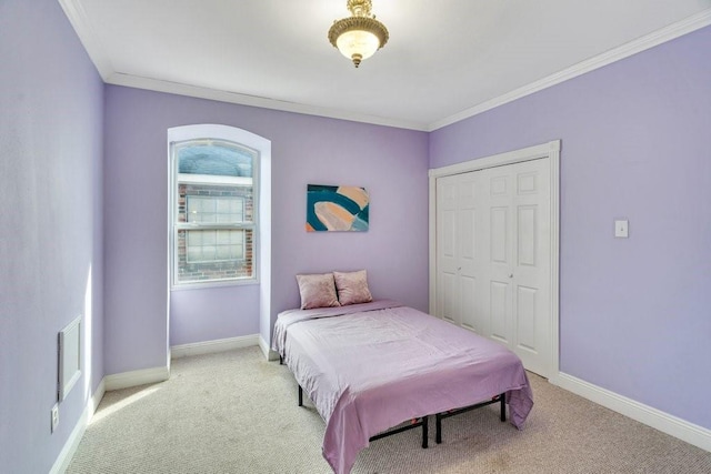 carpeted bedroom with crown molding, baseboards, and a closet