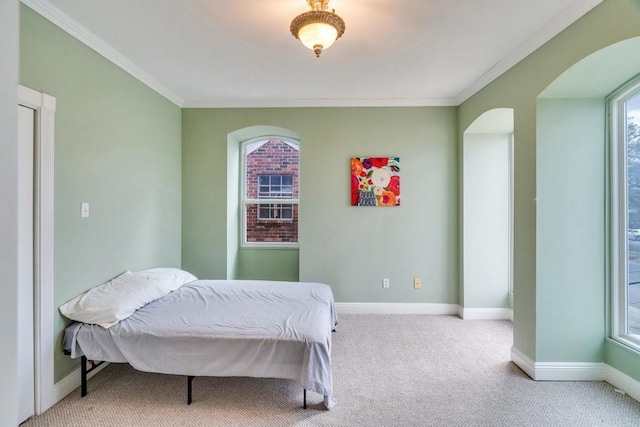 carpeted bedroom featuring crown molding, arched walkways, and baseboards