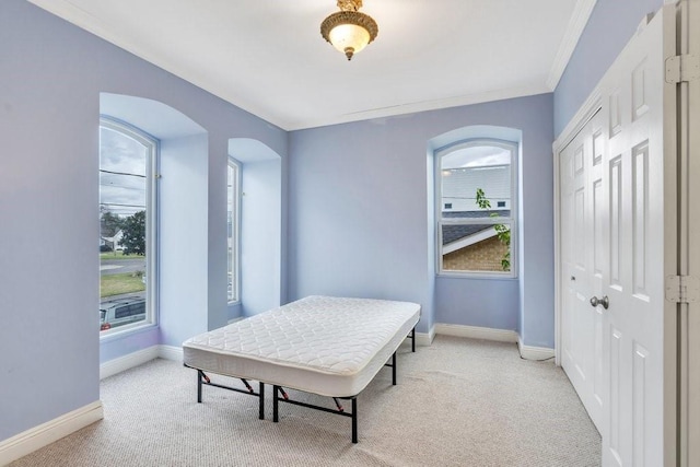 carpeted bedroom featuring crown molding, baseboards, a closet, and arched walkways