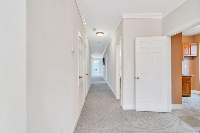 corridor with baseboards, ornamental molding, and light carpet