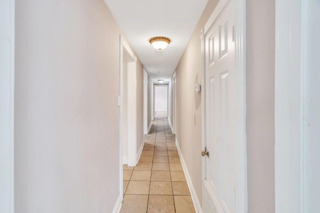 hallway featuring baseboards and light tile patterned floors