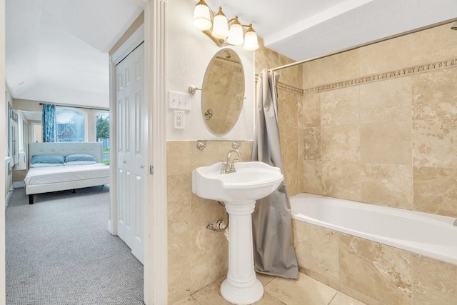 bathroom with tiled shower / bath combo, tile walls, and connected bathroom