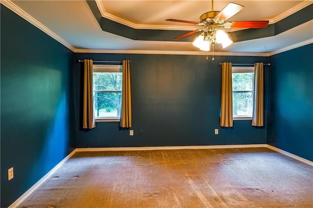 empty room with ceiling fan, baseboards, ornamental molding, a tray ceiling, and carpet flooring