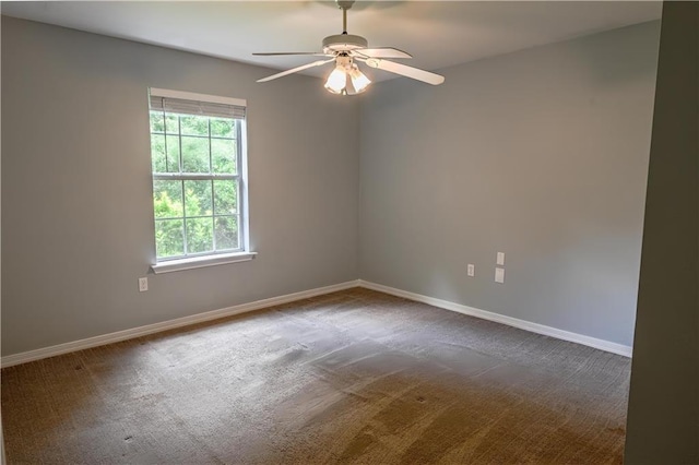 empty room featuring baseboards, ceiling fan, and dark carpet