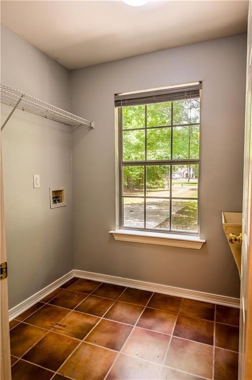 laundry area with dark tile patterned floors, laundry area, a healthy amount of sunlight, and washer hookup