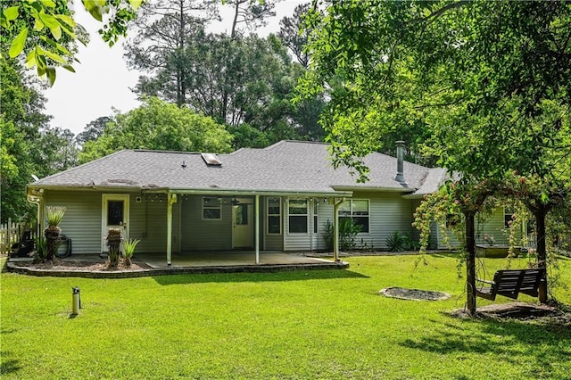 rear view of property with a patio, a shingled roof, and a yard