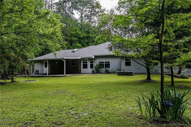 rear view of property featuring a lawn and roof with shingles