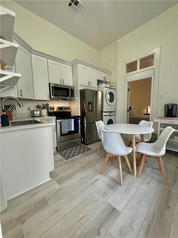 242325 Freret St, New Orleans, LA 70113 - kitchen featuring a sink, appliances with stainless steel finishes, light wood-type flooring, and stacked washer / dryer