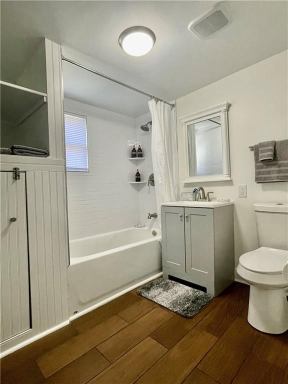 242325 Freret St, New Orleans, LA 70113 - bathroom with visible vents, shower / tub combo with curtain, vanity, wood finished floors, and toilet