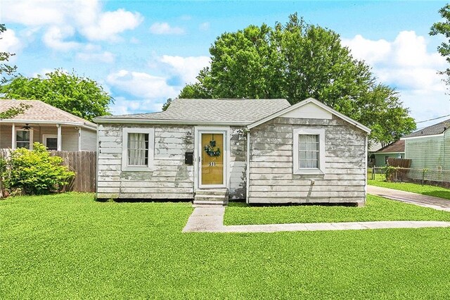 view of front of home featuring fence, entry steps, and a front lawn