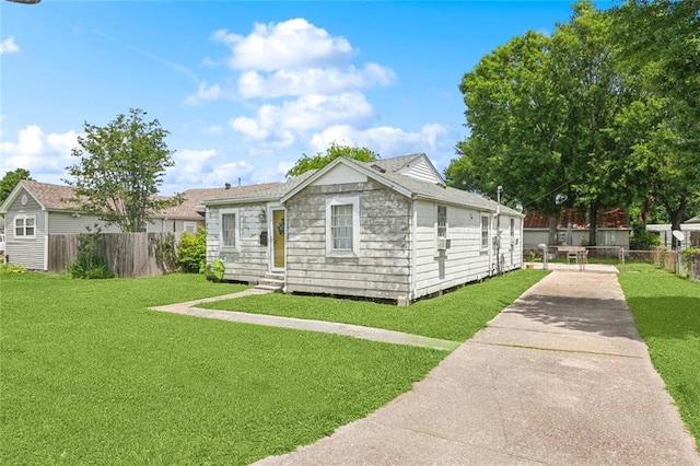 view of front of home with fence, driveway, and a front lawn