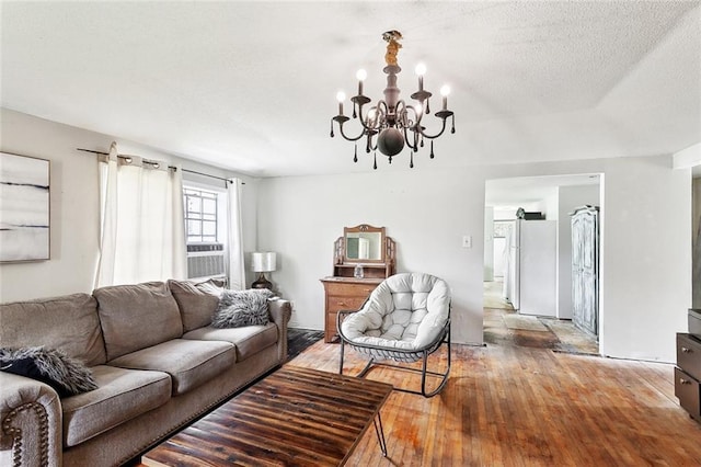 living room featuring a textured ceiling, an inviting chandelier, and light wood-type flooring