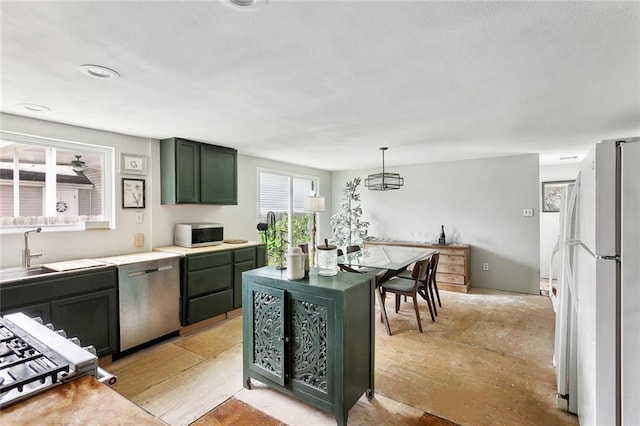kitchen with freestanding refrigerator, light countertops, green cabinetry, a sink, and dishwasher