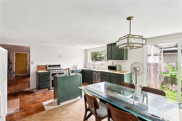 kitchen with green cabinetry, appliances with stainless steel finishes, light countertops, a chandelier, and decorative light fixtures