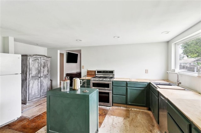 kitchen with green cabinetry, a sink, a center island, freestanding refrigerator, and range with two ovens