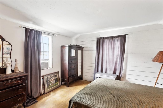 bedroom featuring wooden walls, vaulted ceiling, and light carpet