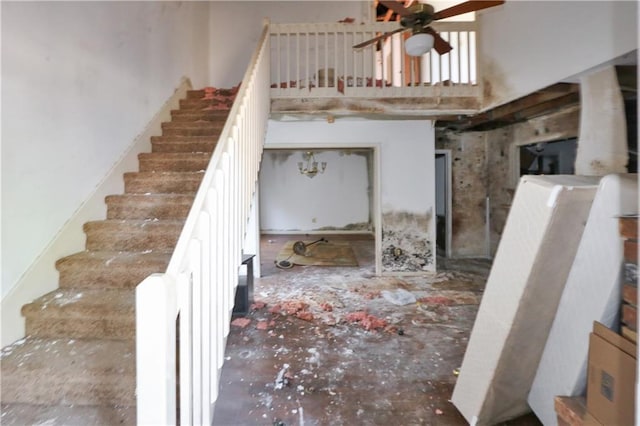 staircase featuring a towering ceiling and ceiling fan
