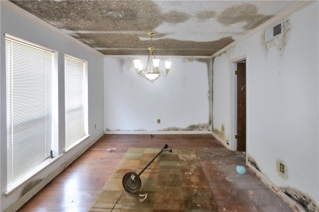 unfurnished dining area featuring visible vents, ornamental molding, wood finished floors, and a notable chandelier