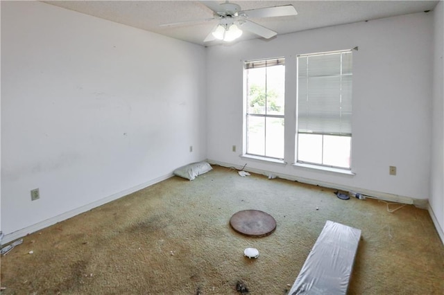 carpeted empty room with baseboards and a ceiling fan